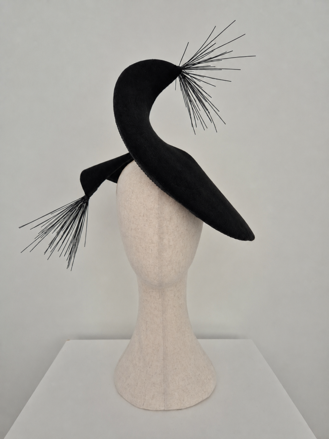 Black hat with decorative elements on a mannequin head against a gray background