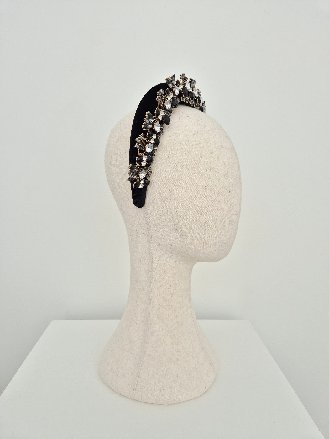 Black headband with rhinestones on a mannequin head against a white background side view