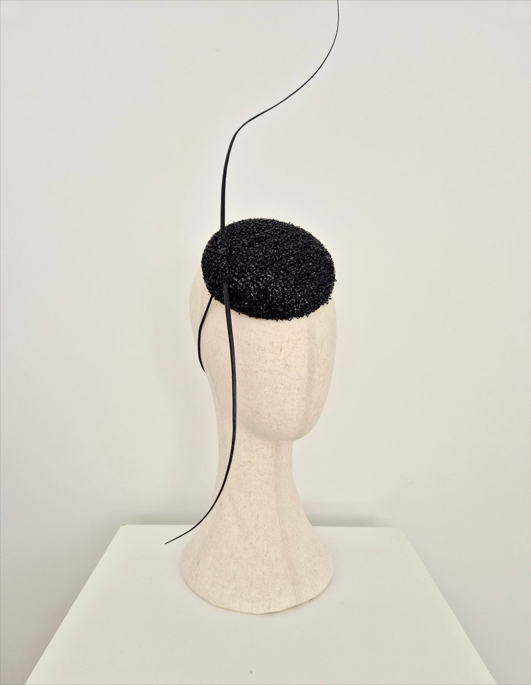 Black textured headpiece on a mannequin head against a white background side view