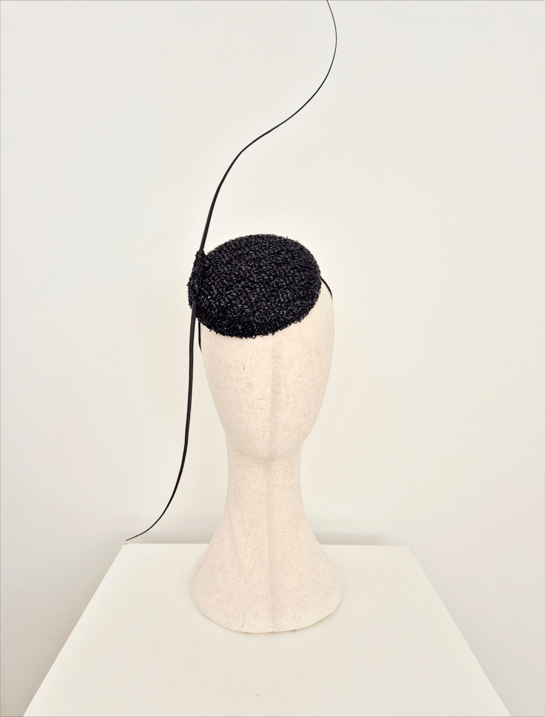 Black textured headpiece on a mannequin head against a white background