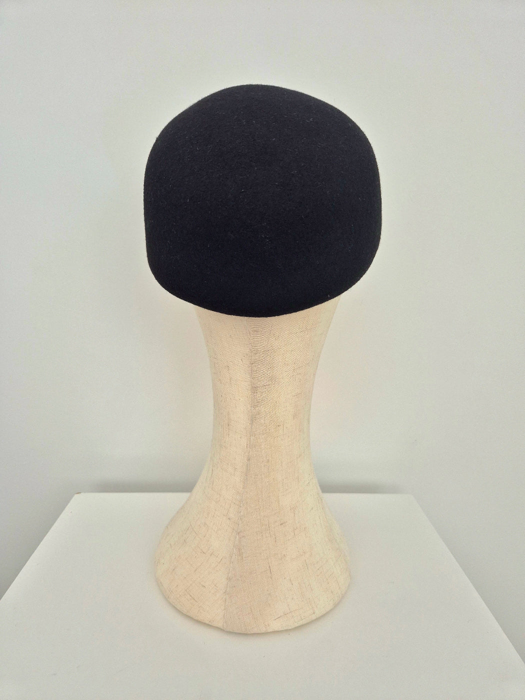 Black cap on a mannequin head against a white background back view