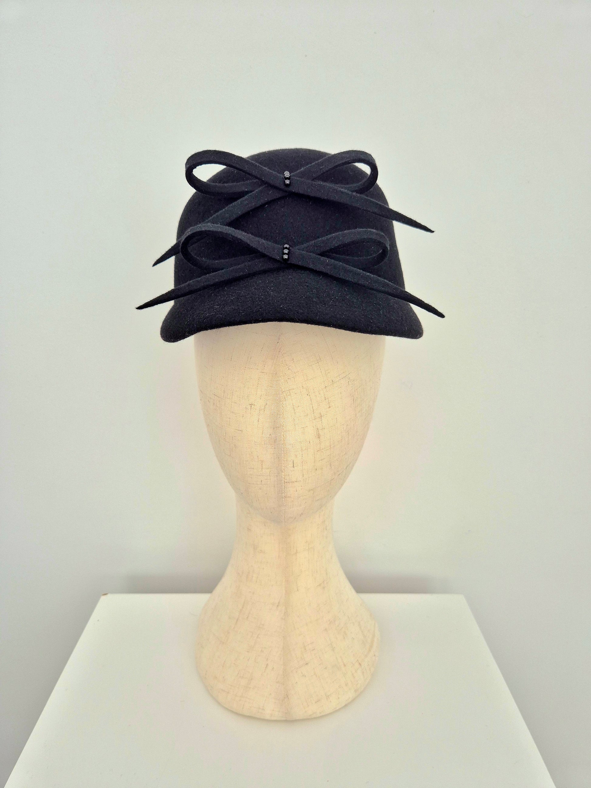 Black hat cap with 2 bows on the front on a mannequin head against a white background