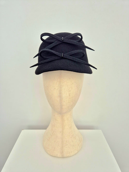 Black hat cap with 2 bows on the front on a mannequin head against a white background