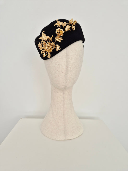 Black headpiece wool felt with gold floral designs on a mannequin head against a white background