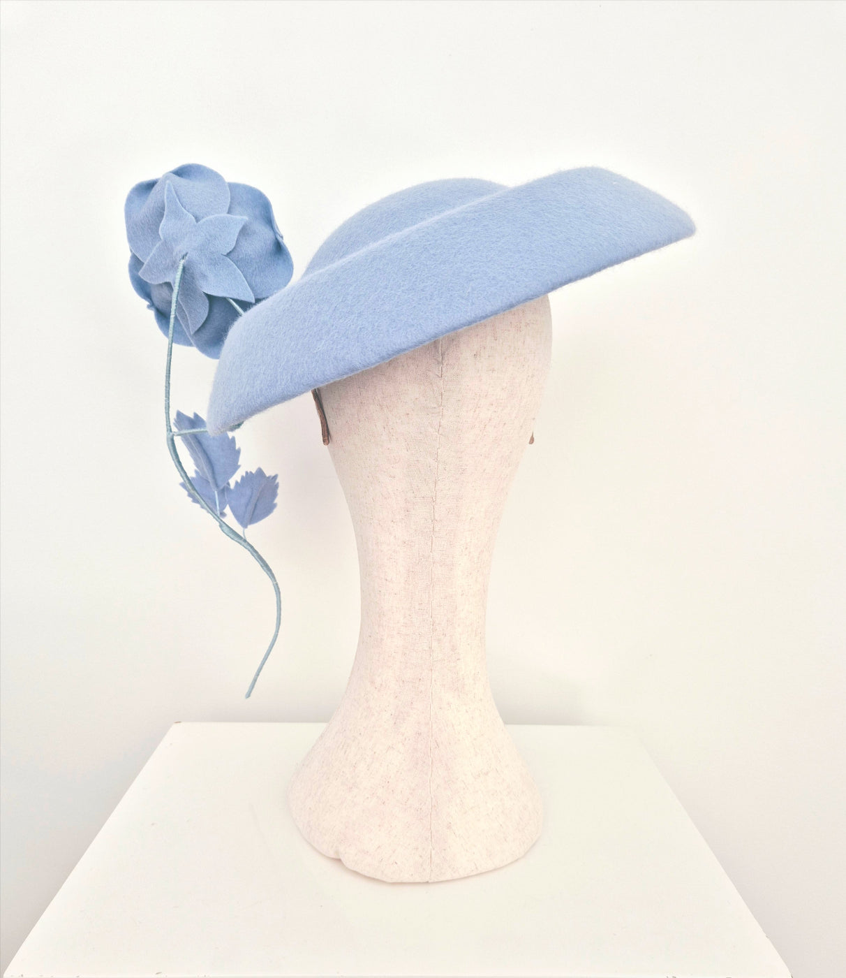 Light blue hat with floral decorations on a mannequin head against a white background back view