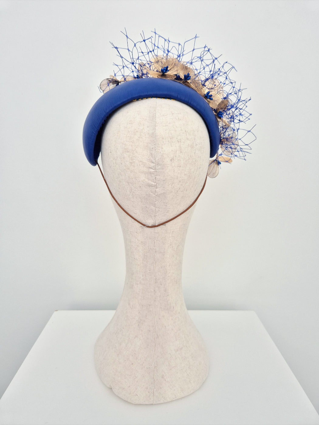 Blue decorative headpiece on a mannequin head against a white background back view