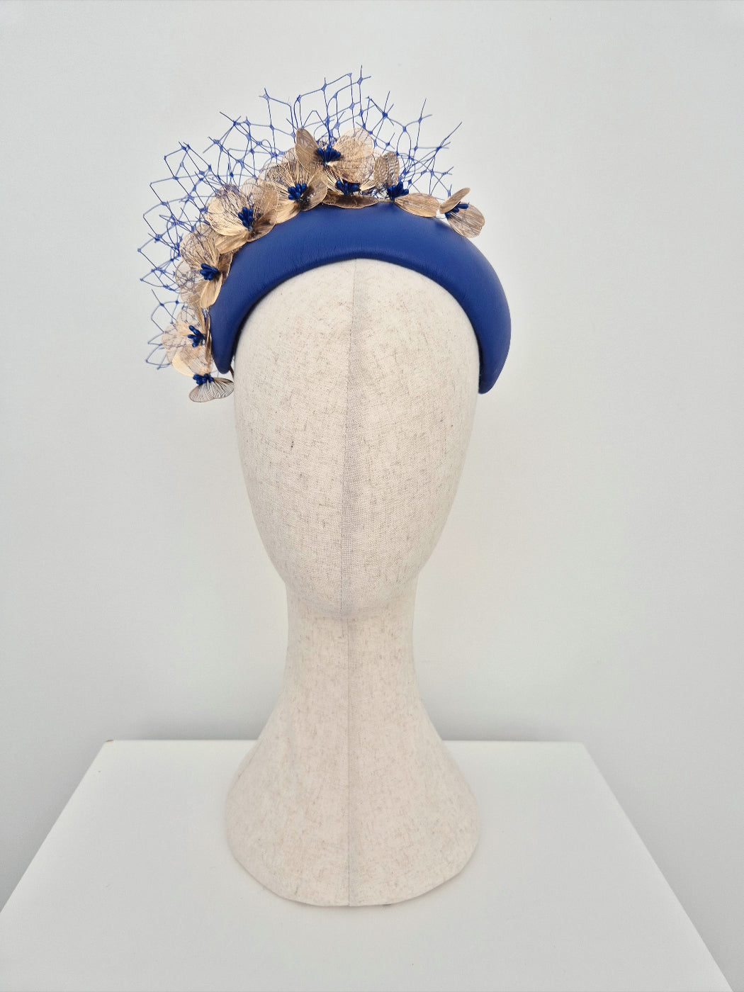 Blue headband with gold floral elements on a mannequin head against a white background