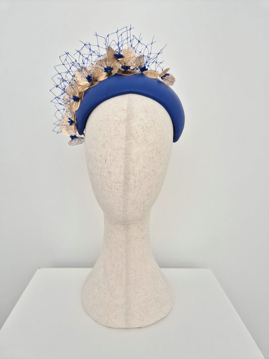 Blue headband with gold floral elements on a mannequin head against a white background
