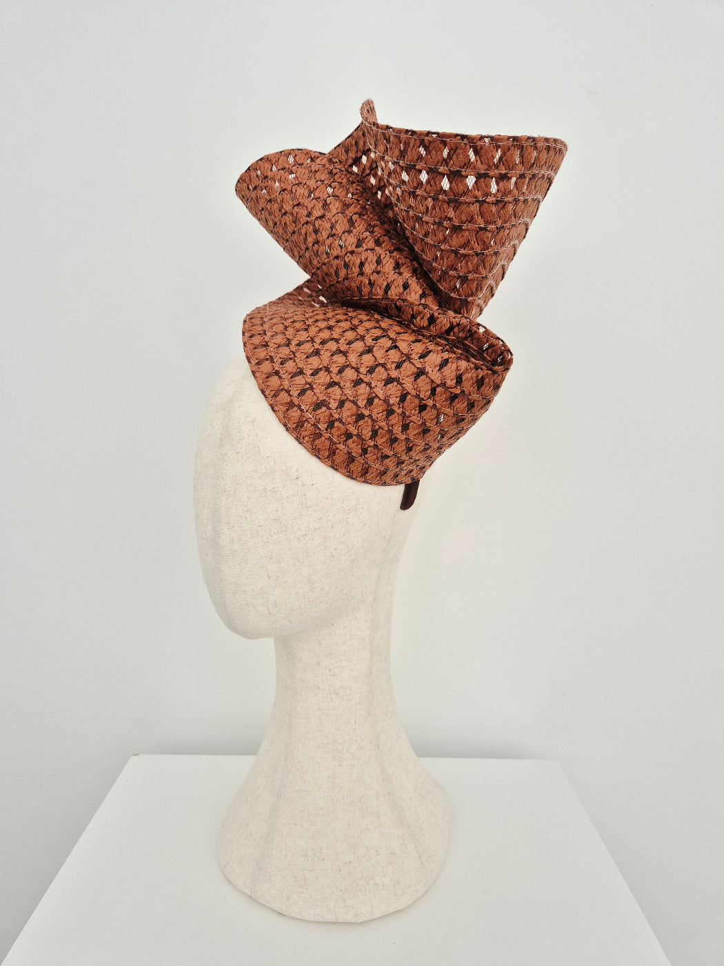 Brown straw headpiece on a mannequin head against a white background side view