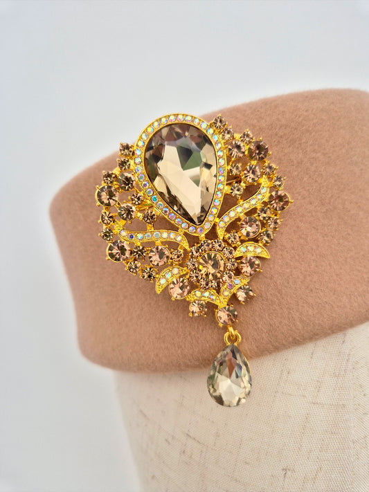 Decorative brooch with gemstones on a mannequin head against a neutral background close up