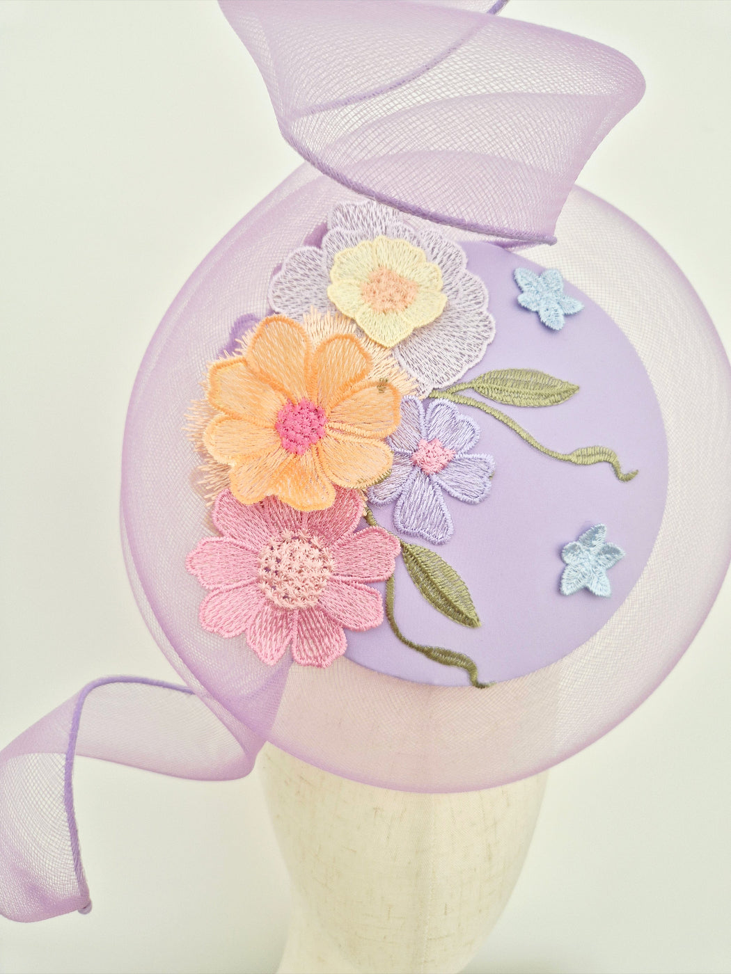 close up percher headpiece in lilac with floral lace detail on a manniquin head 