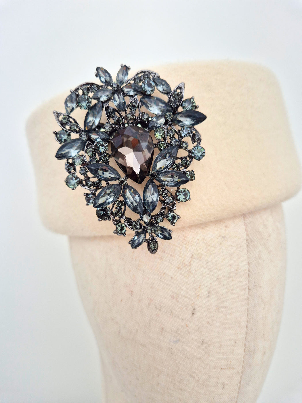 Decorative brooch with intricate design on a mannequin head against a white background