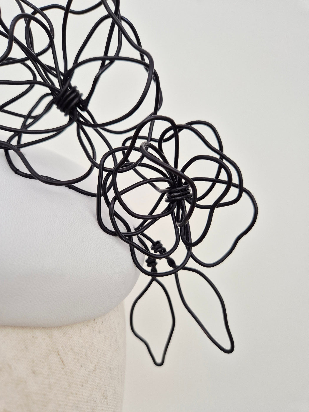 close up white headpiece with black floral wirework