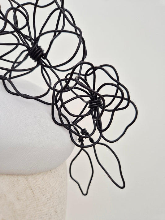 close up white headpiece with black floral wirework
