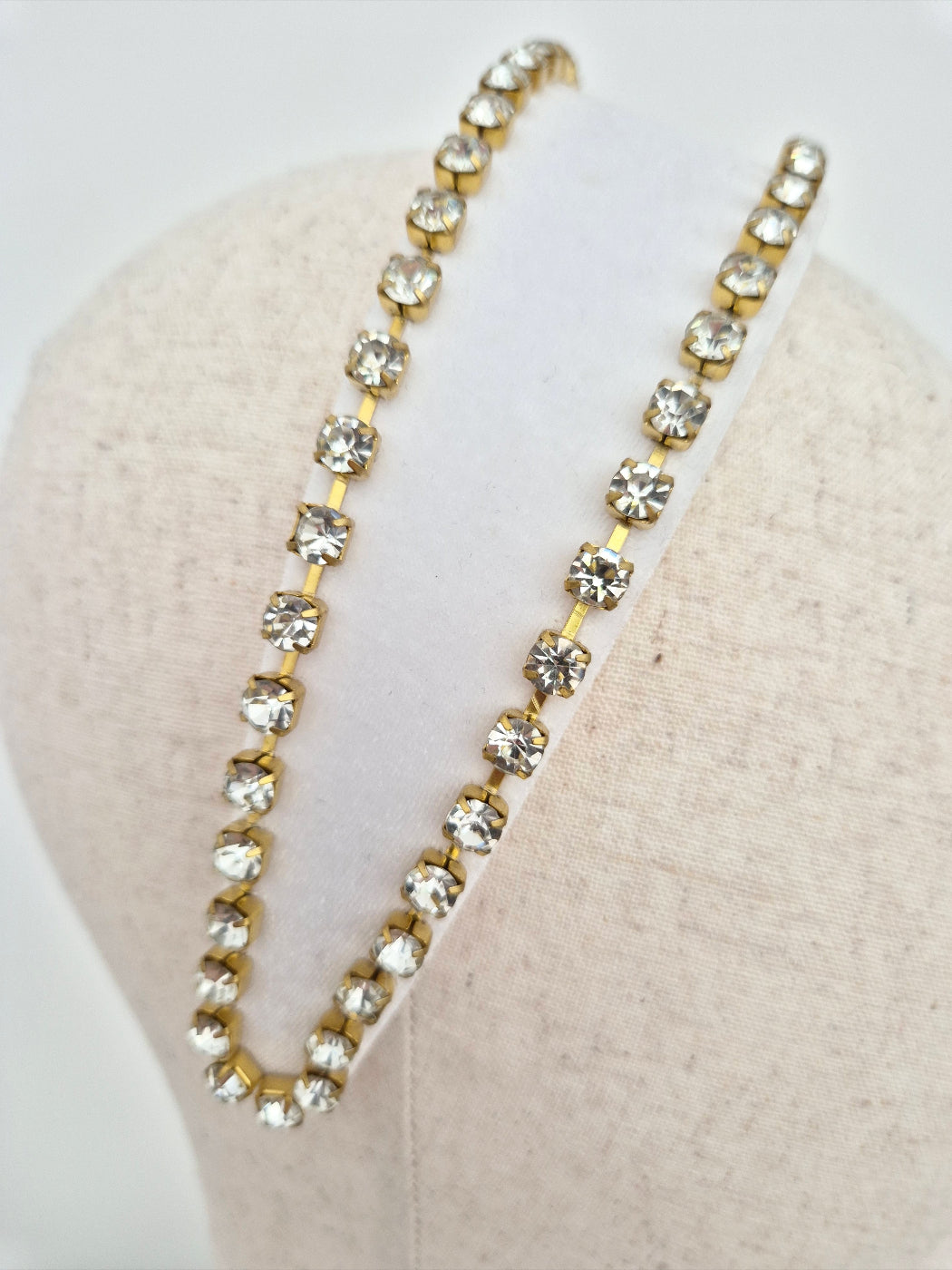 close up white velvet headband with gold set rhinestone trim on a mannequin head