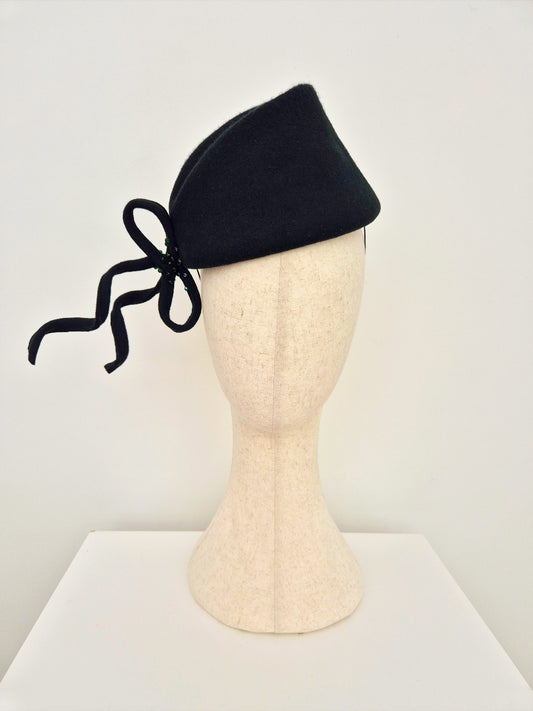 dark forest green headpiece with a bow on a mannequin head against a white background