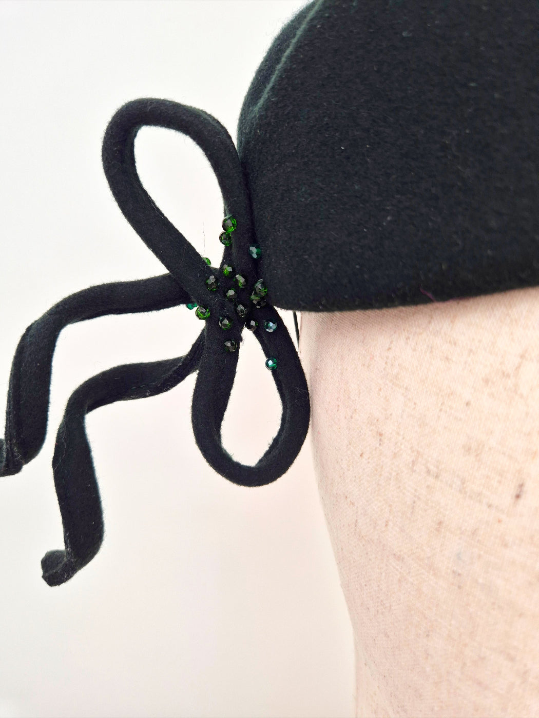 dark forest green bow on the felt topper headpiece hair accessory with green beads on a white background close up