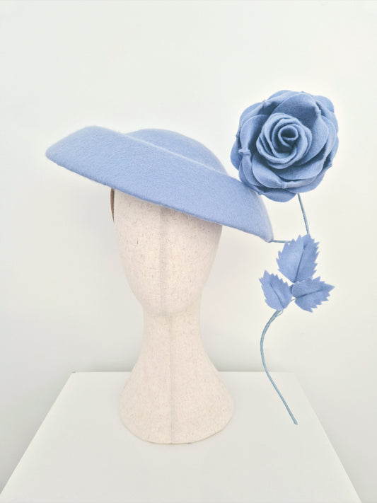 dusty blue hat with a matching flower on a mannequin head against a white background