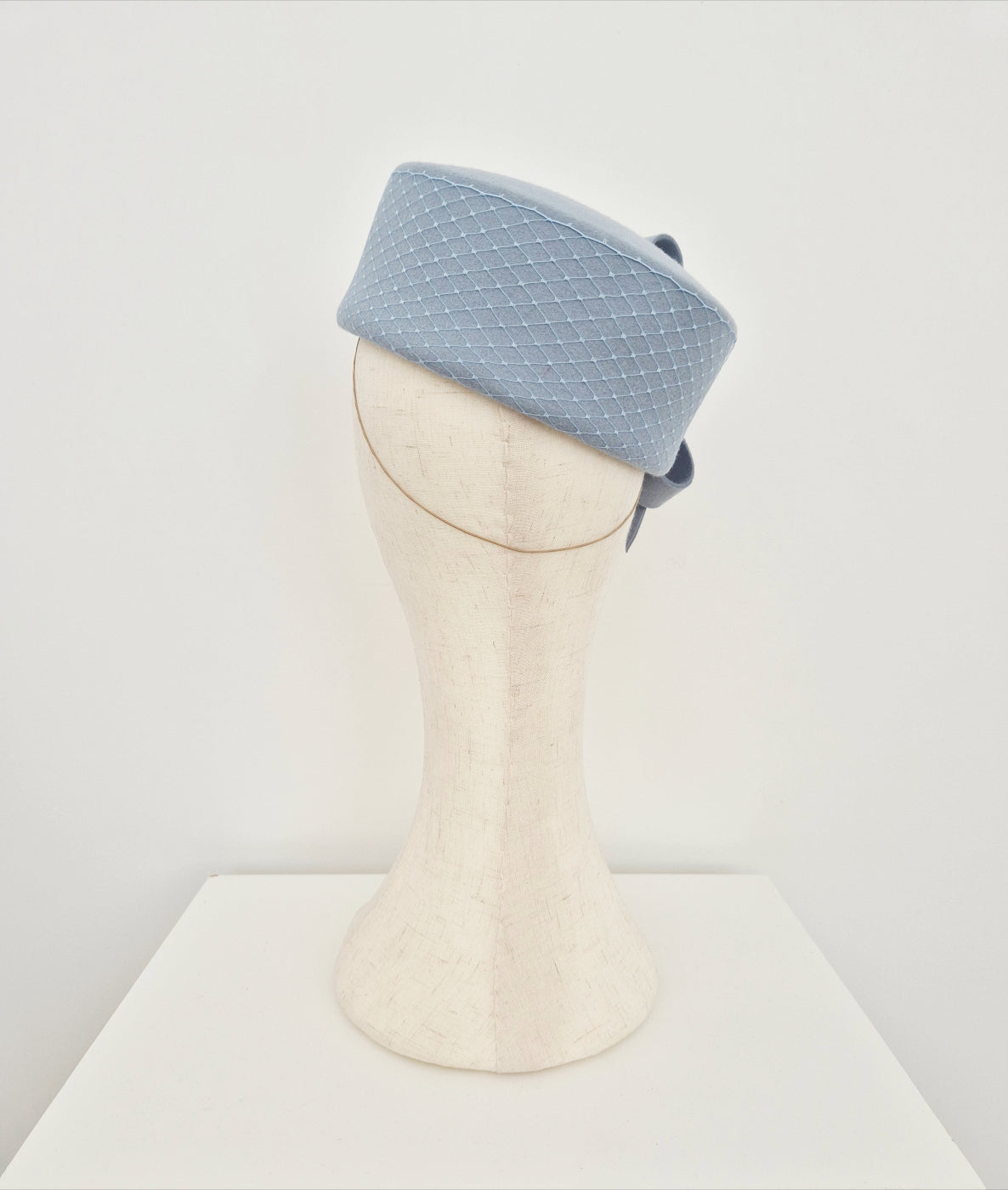 Light blue textured pillbox headpiece on a mannequin head against a white background