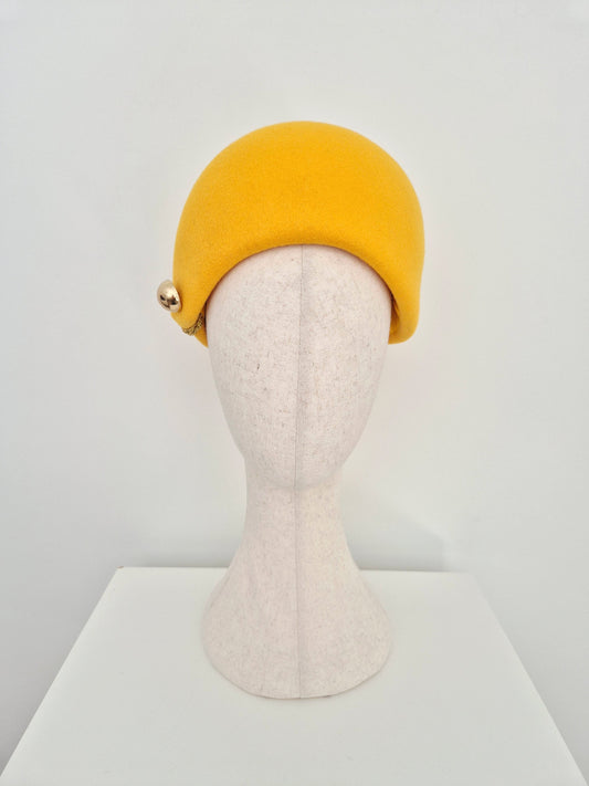 A  yellow felt hat on a  mannequin head, set against a plain white background.