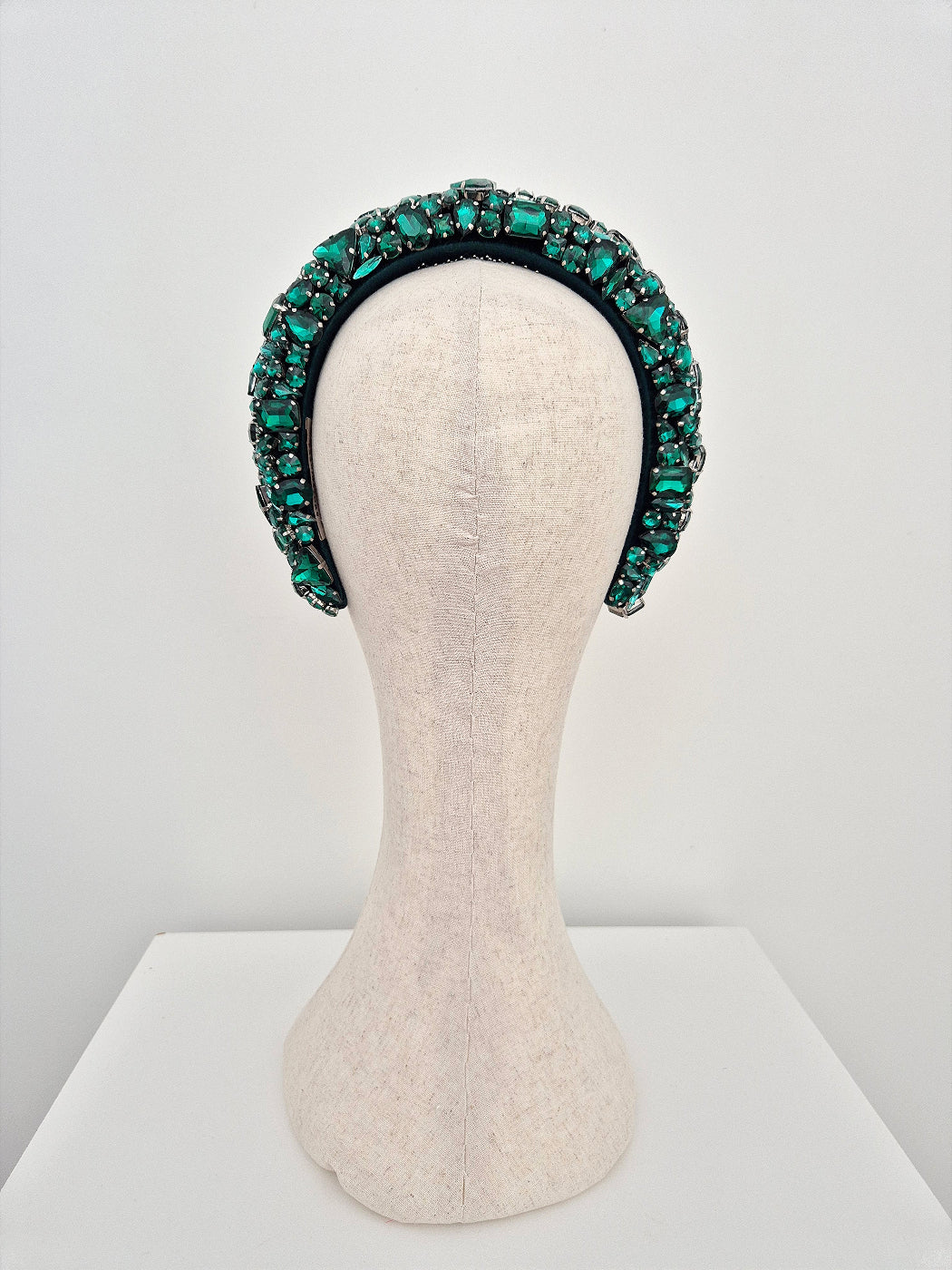 Green beaded headband on a mannequin head against a white background back view