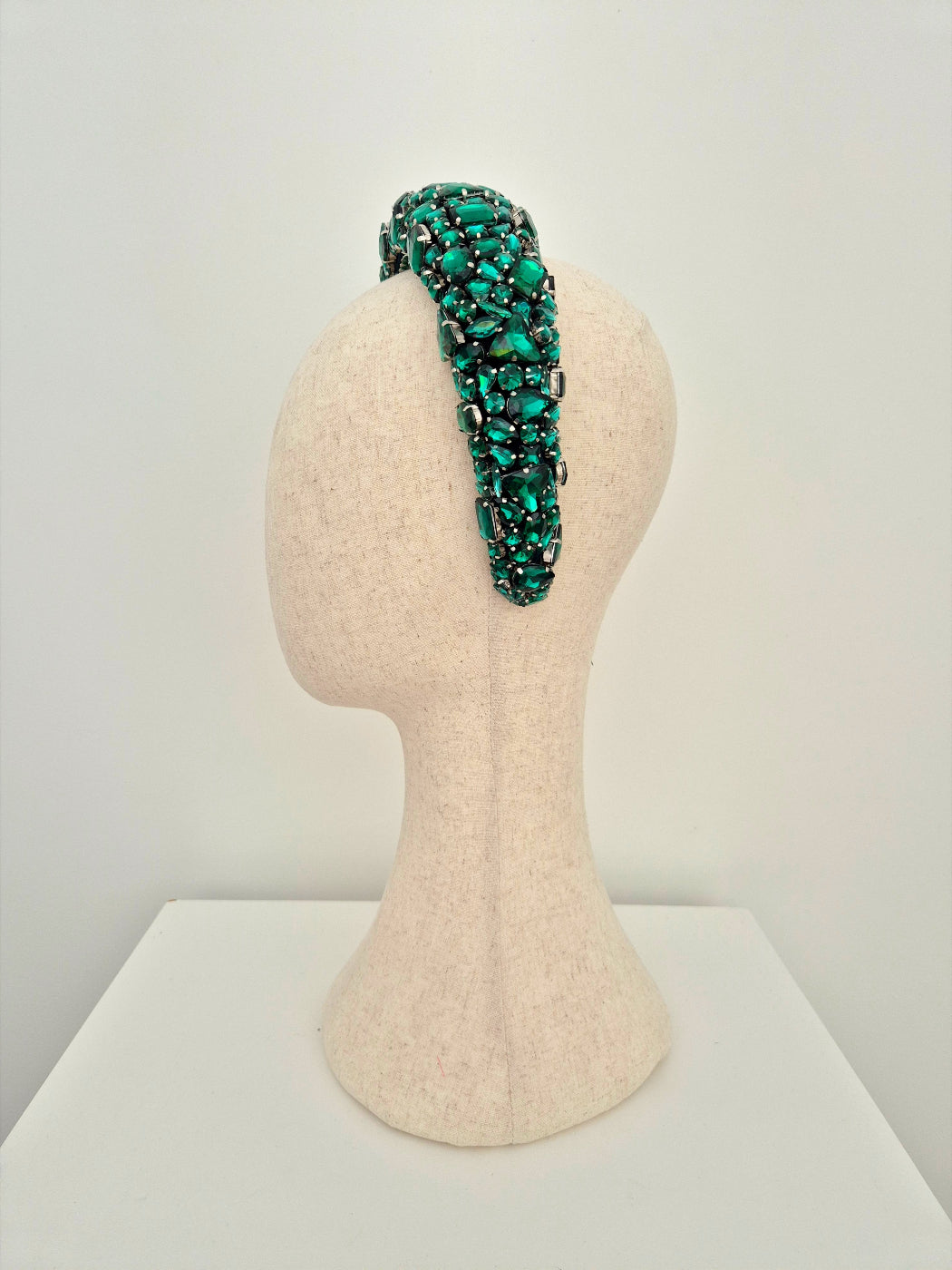 Green beaded headband on a mannequin head against a white background side view