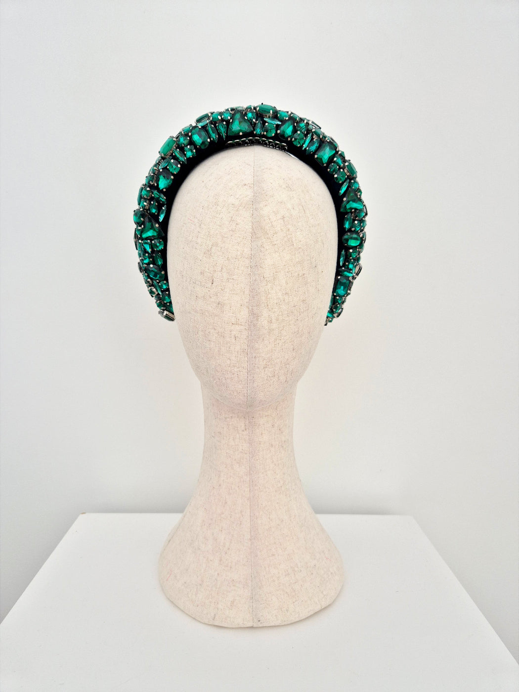 Green beaded headband on a mannequin head against a white background