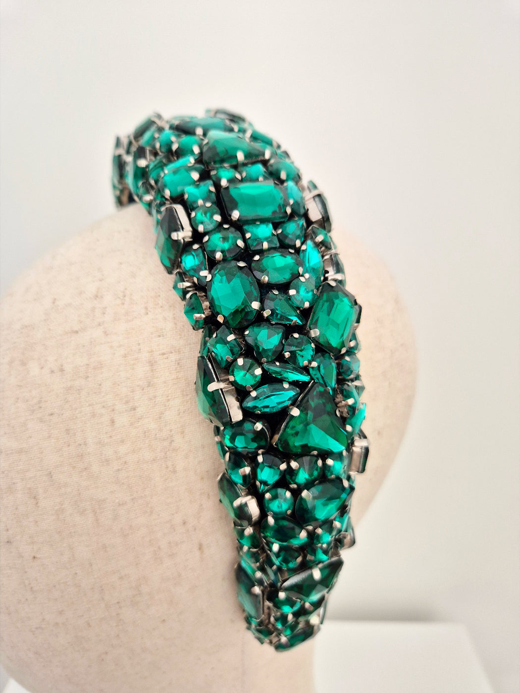 Green gemstone headband on a mannequin head against a white background close up