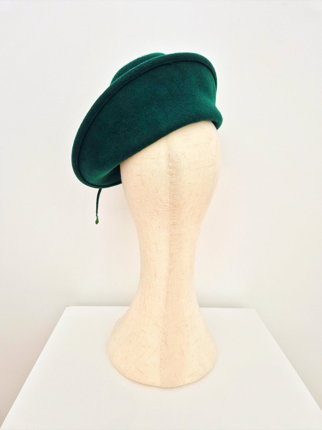 Green hat on a mannequin head against a white background back view