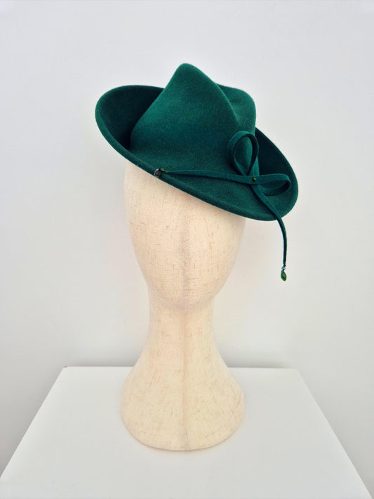 Green felt hat on a mannequin head against a white background