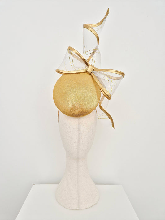 Gold headpiece with a large bow on a mannequin head against a white background