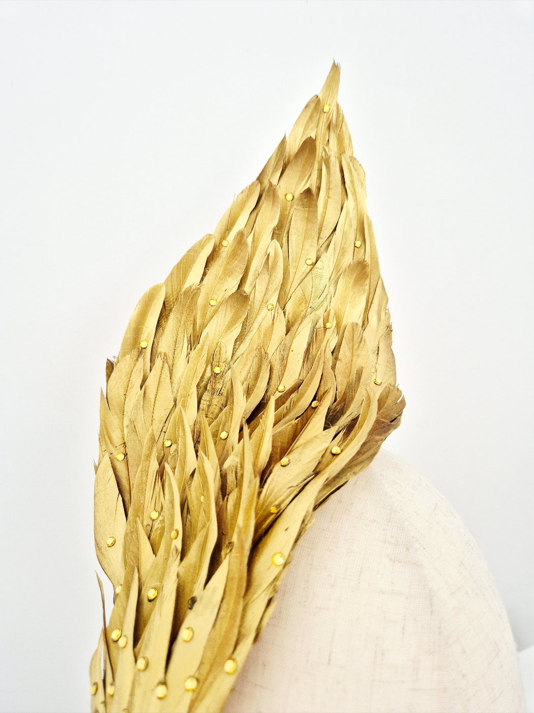 Gold feather headpiece on a white back ground close up