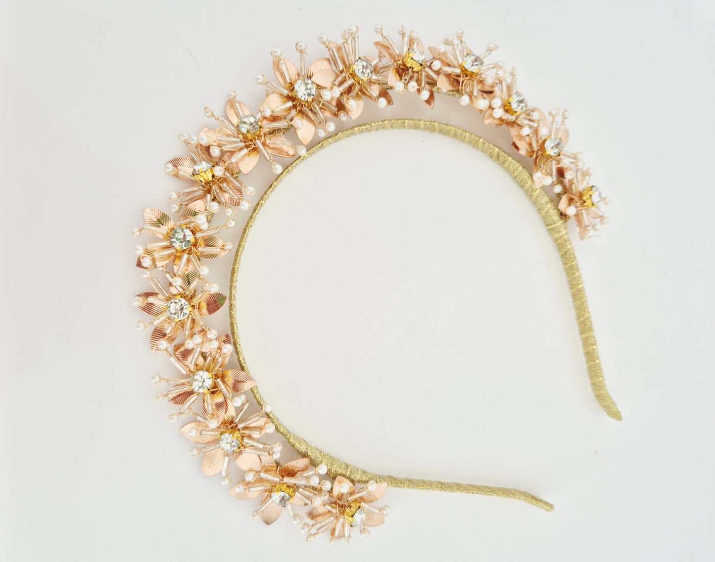 gold headband with floral  details on a light background flat lay
