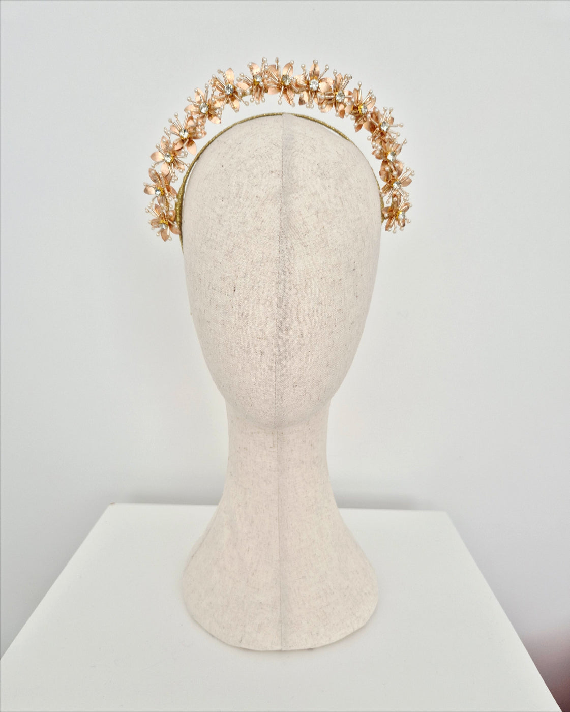 Gold floral headband on a mannequin head against a white background