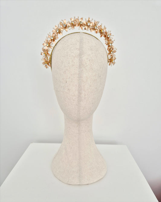 Gold floral headband on a mannequin head against a white background