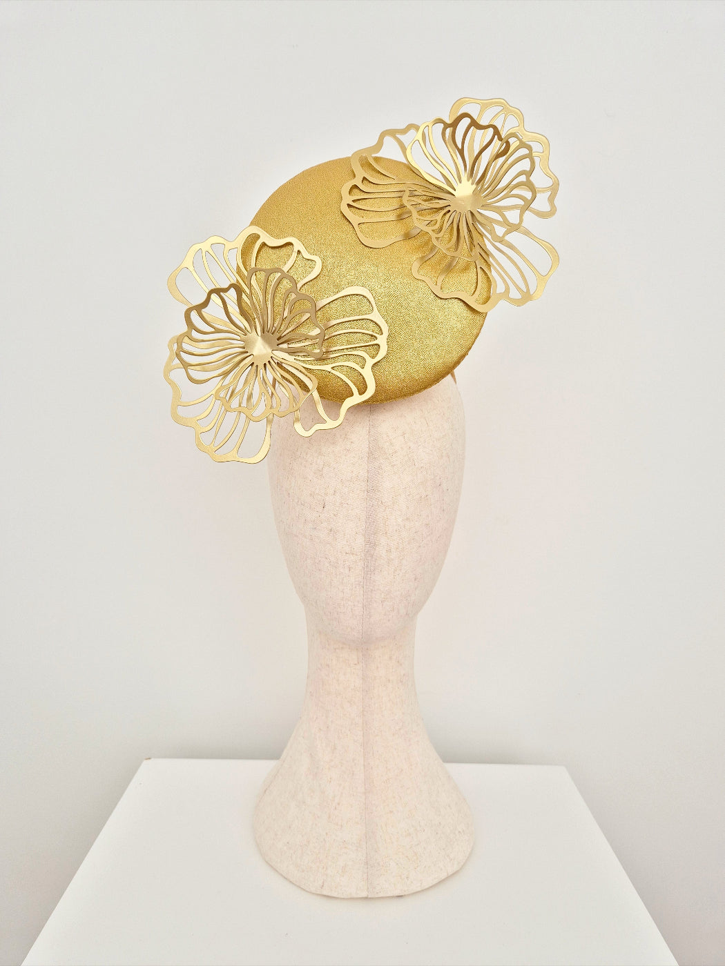Gold floral headpiece on a mannequin head against a white background