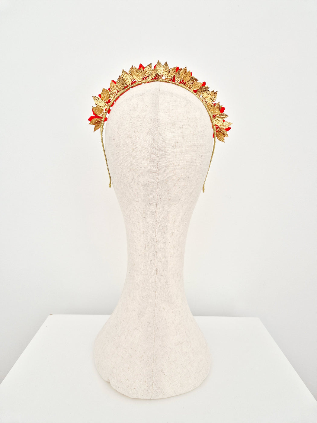 Gold and red floral headband on a mannequin head against a white background back view