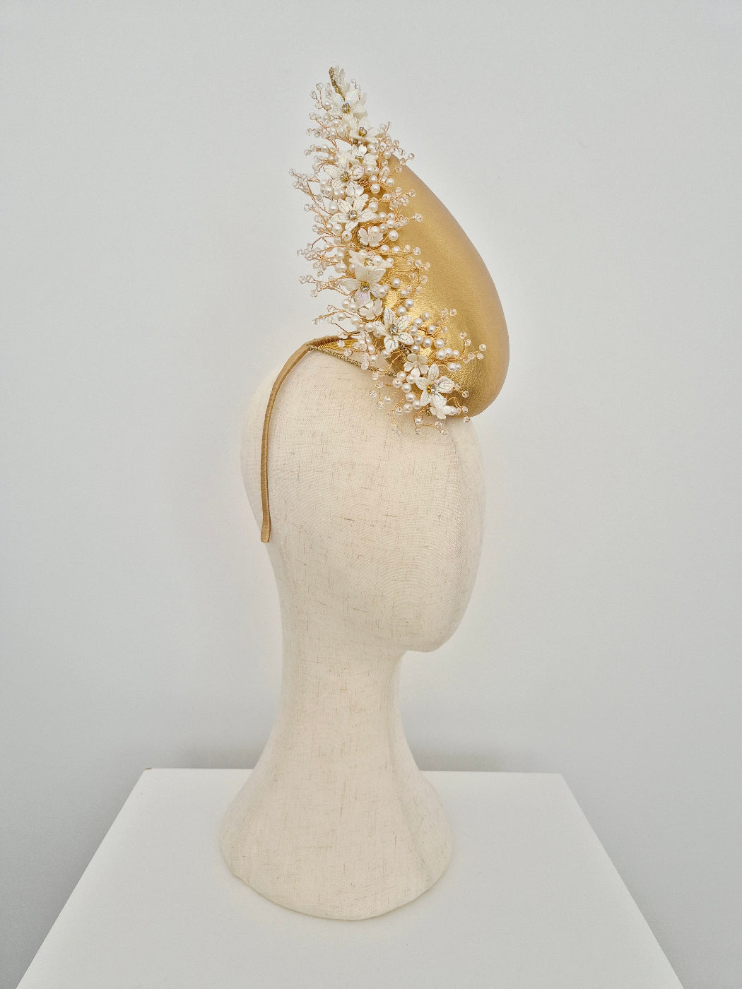gold headpiece percher with pearl and crystal embellishments on a manniquin head against a white background side view