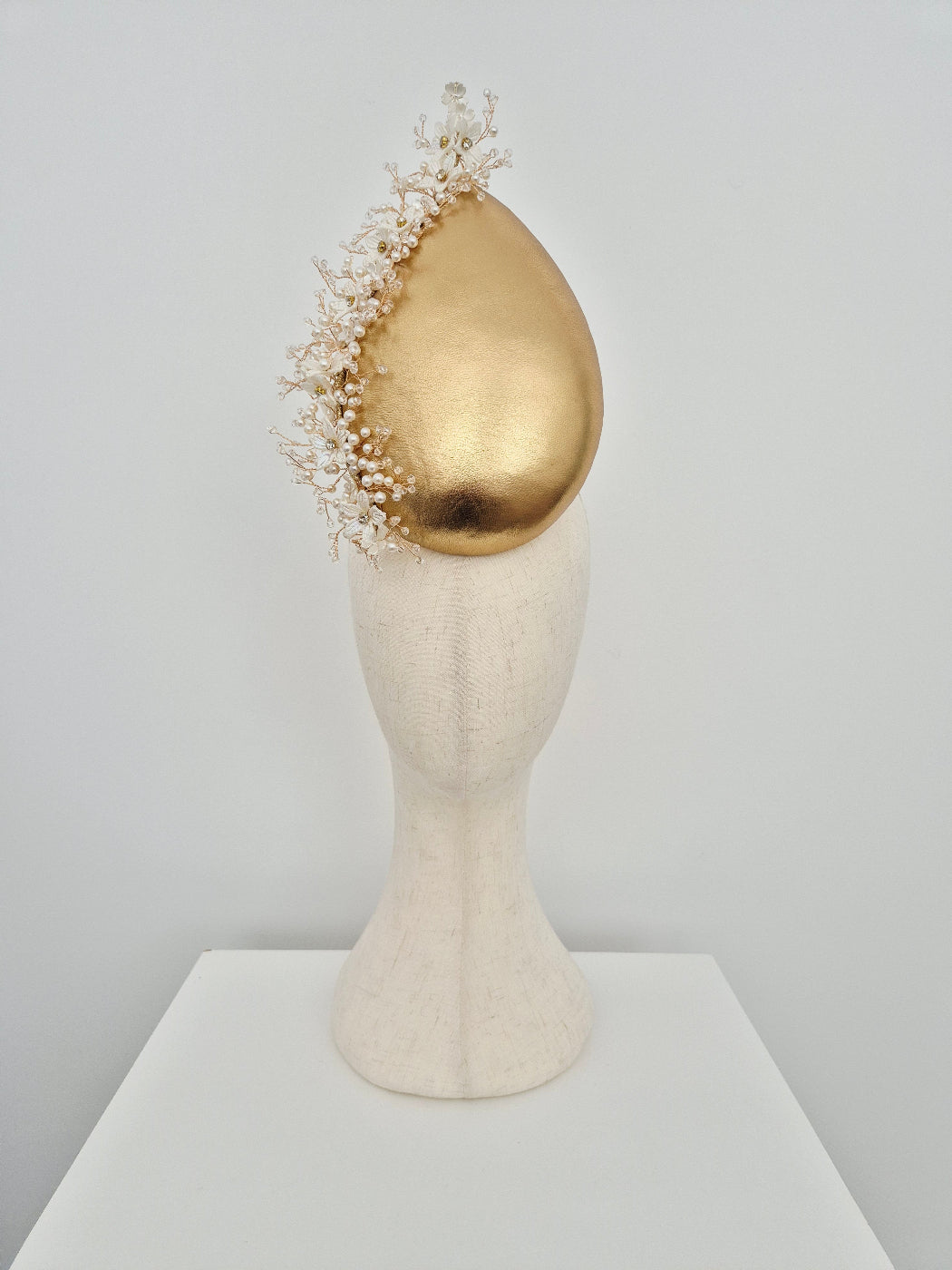  gold leather teardrop headpiece with pearl and crystal vine against a  white  background