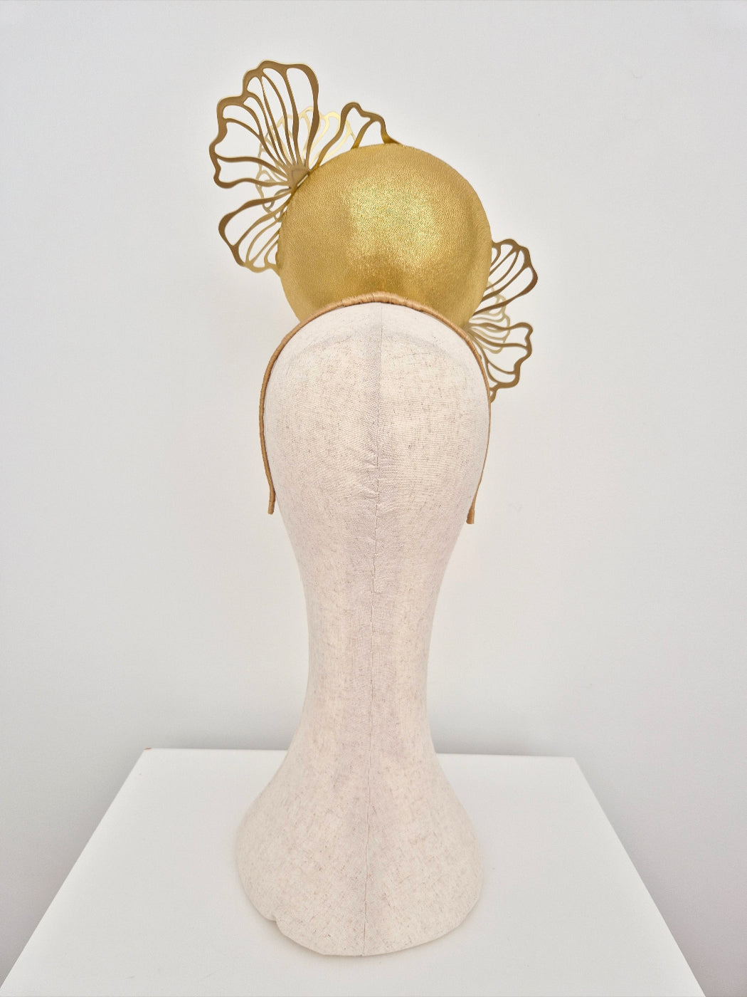 Gold headpiece on a mannequin head against a white background back view