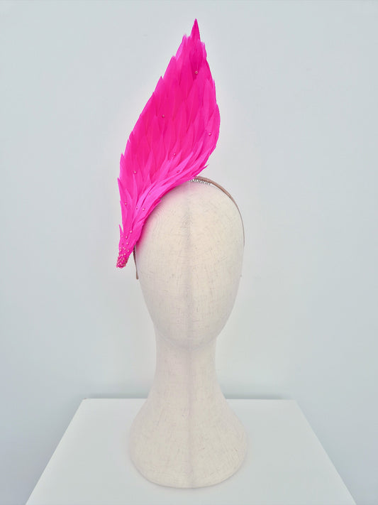 Mannequin head with a bright pink feathered headdress on a white background