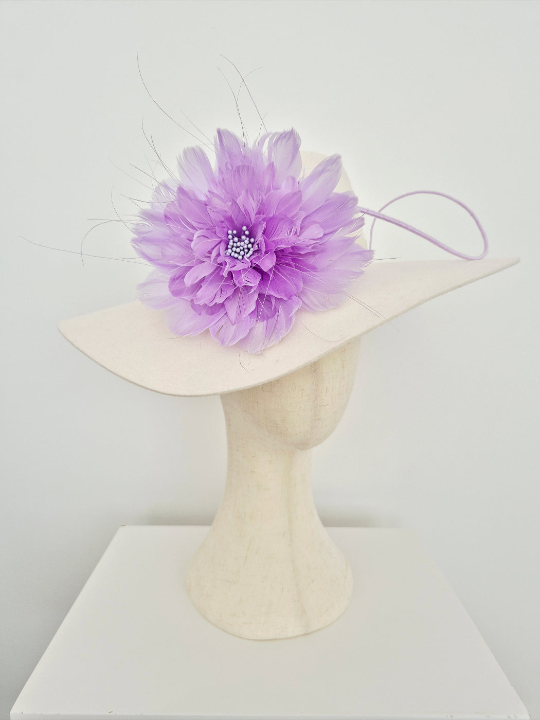ivory felt hat with a large purple flower on a white background side view