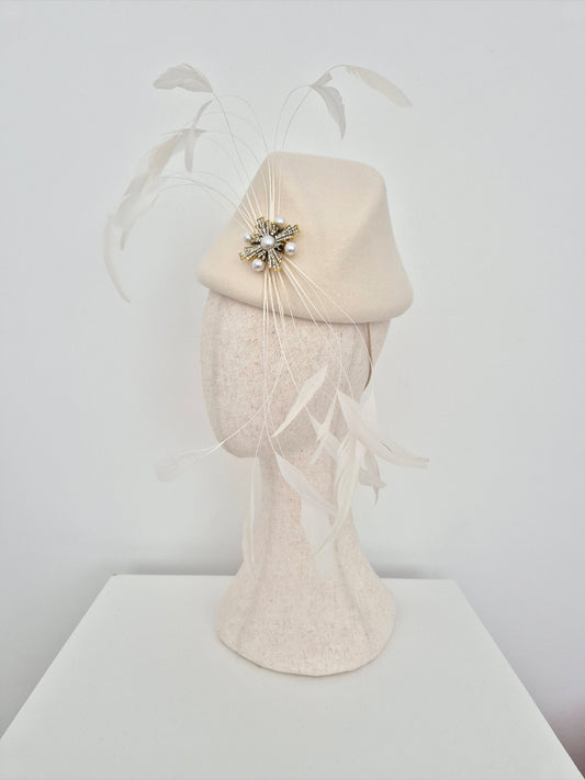 ivory felt headpiece with feather accents on a mannequin head against a white background side view
