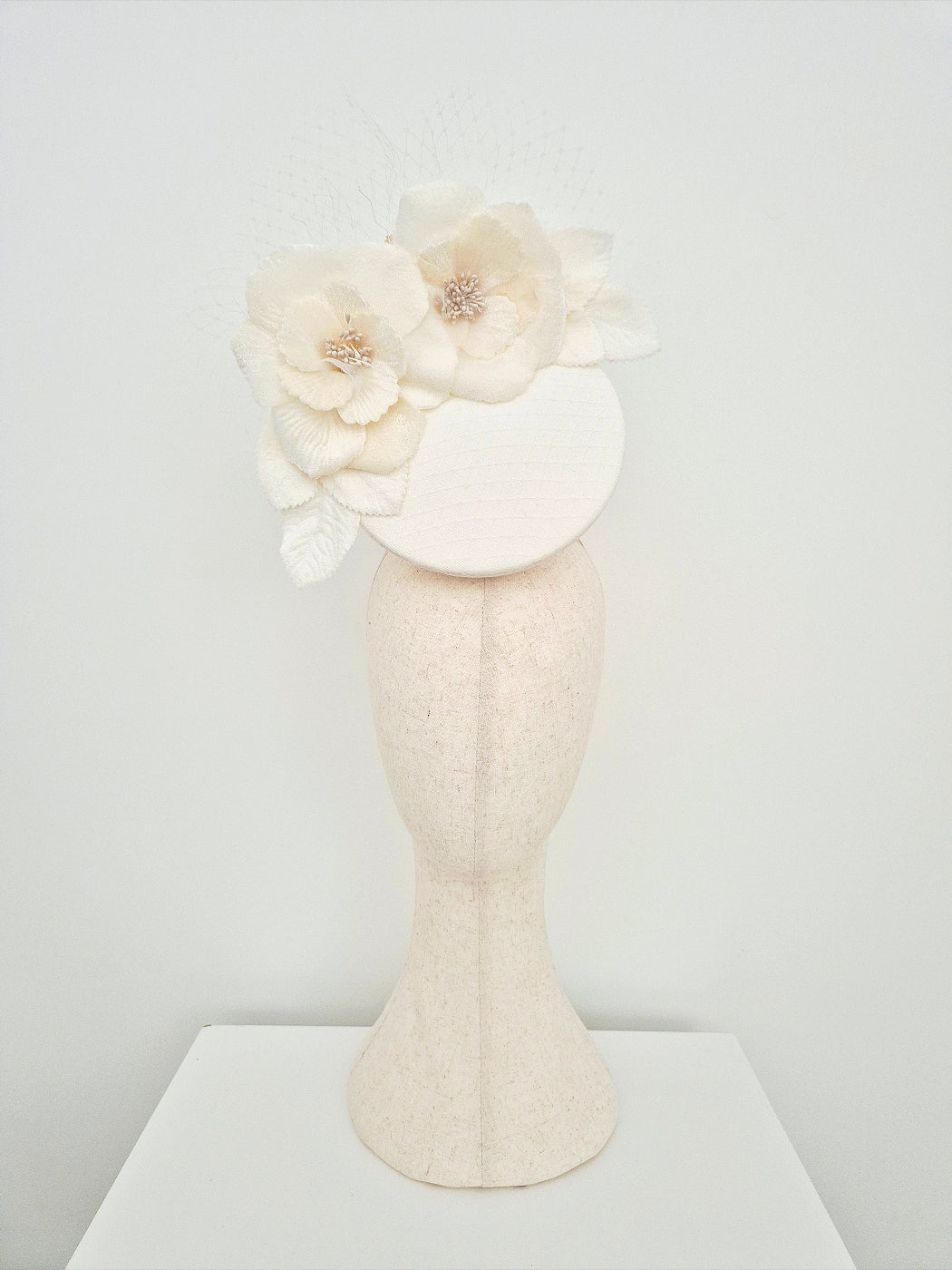 Ivory floral headpiece on a mannequin head against a light gray background