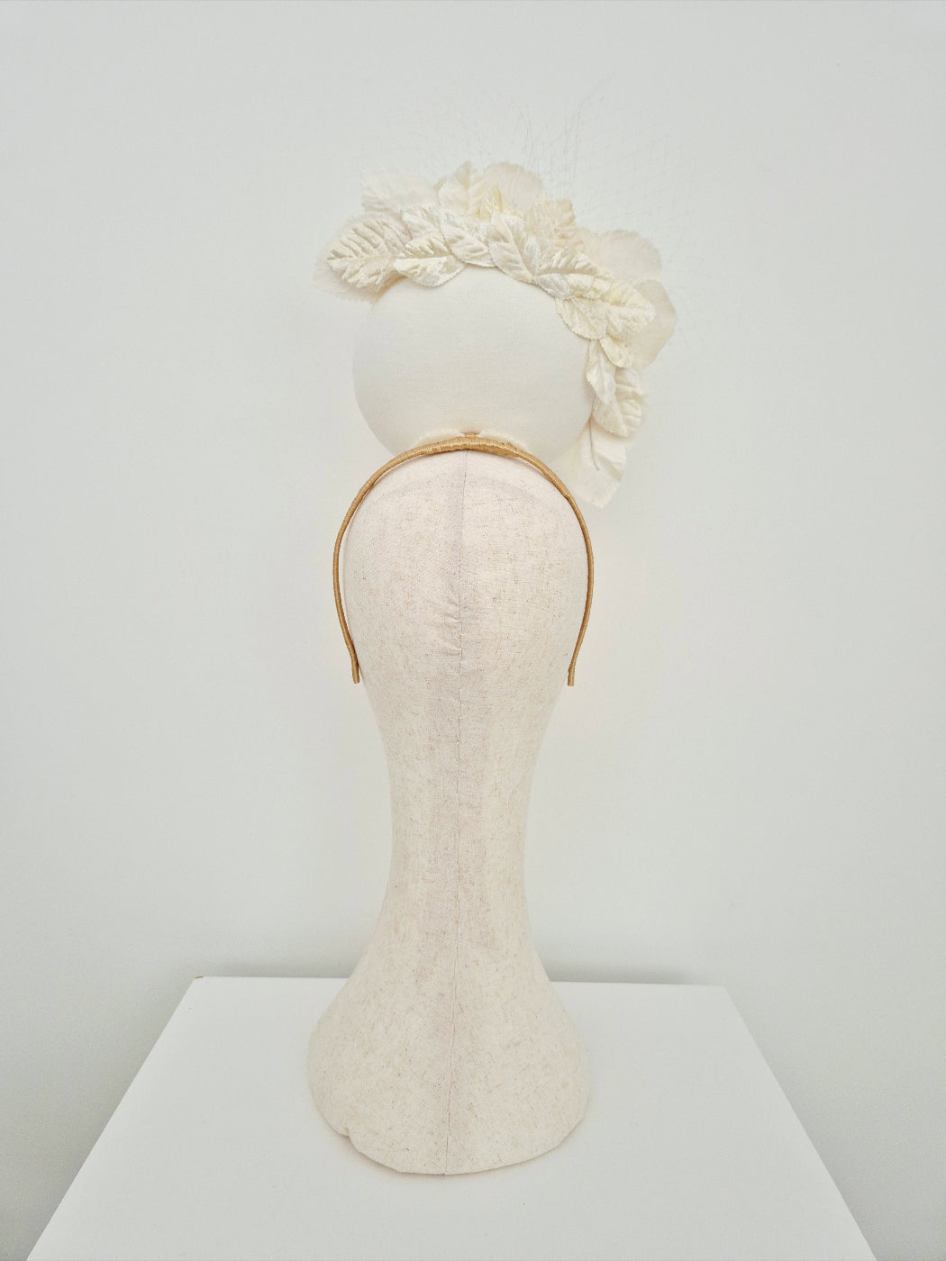 Mannequin head with a ivory percher headpiece on a white background back view