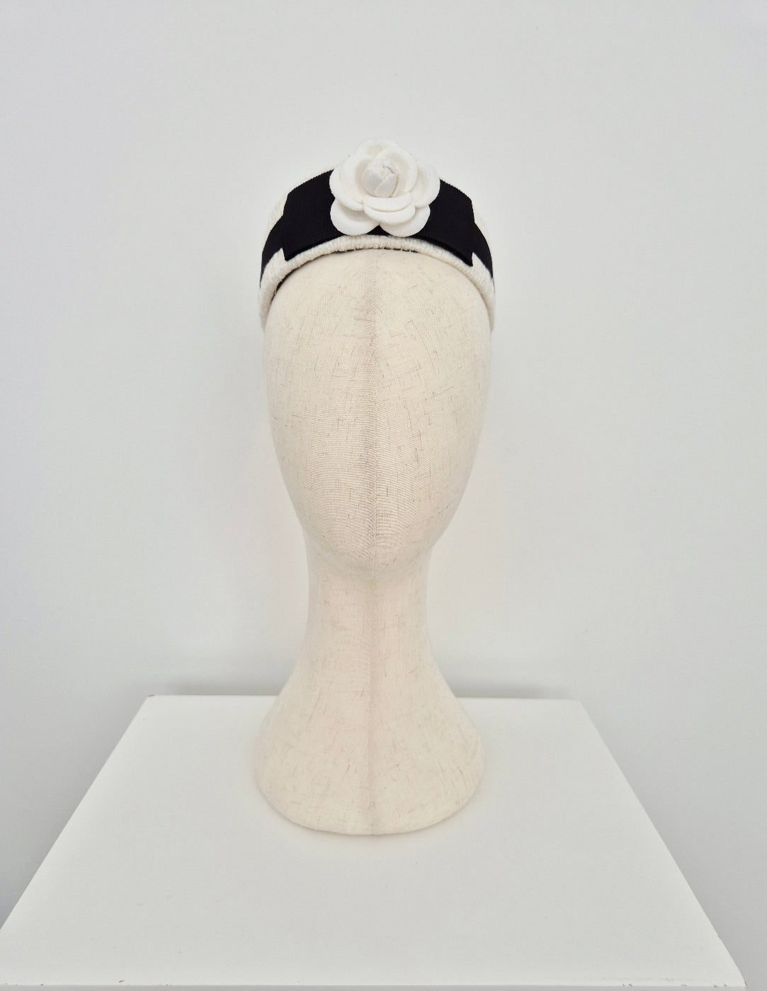 Mannequin head with a ivory tweed headpiece pillbox with a flower on a white background
