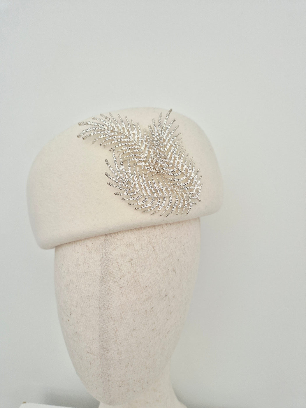 ivory wool felt  beret with decorative silver fern rhinestone embellishment on a white background close up