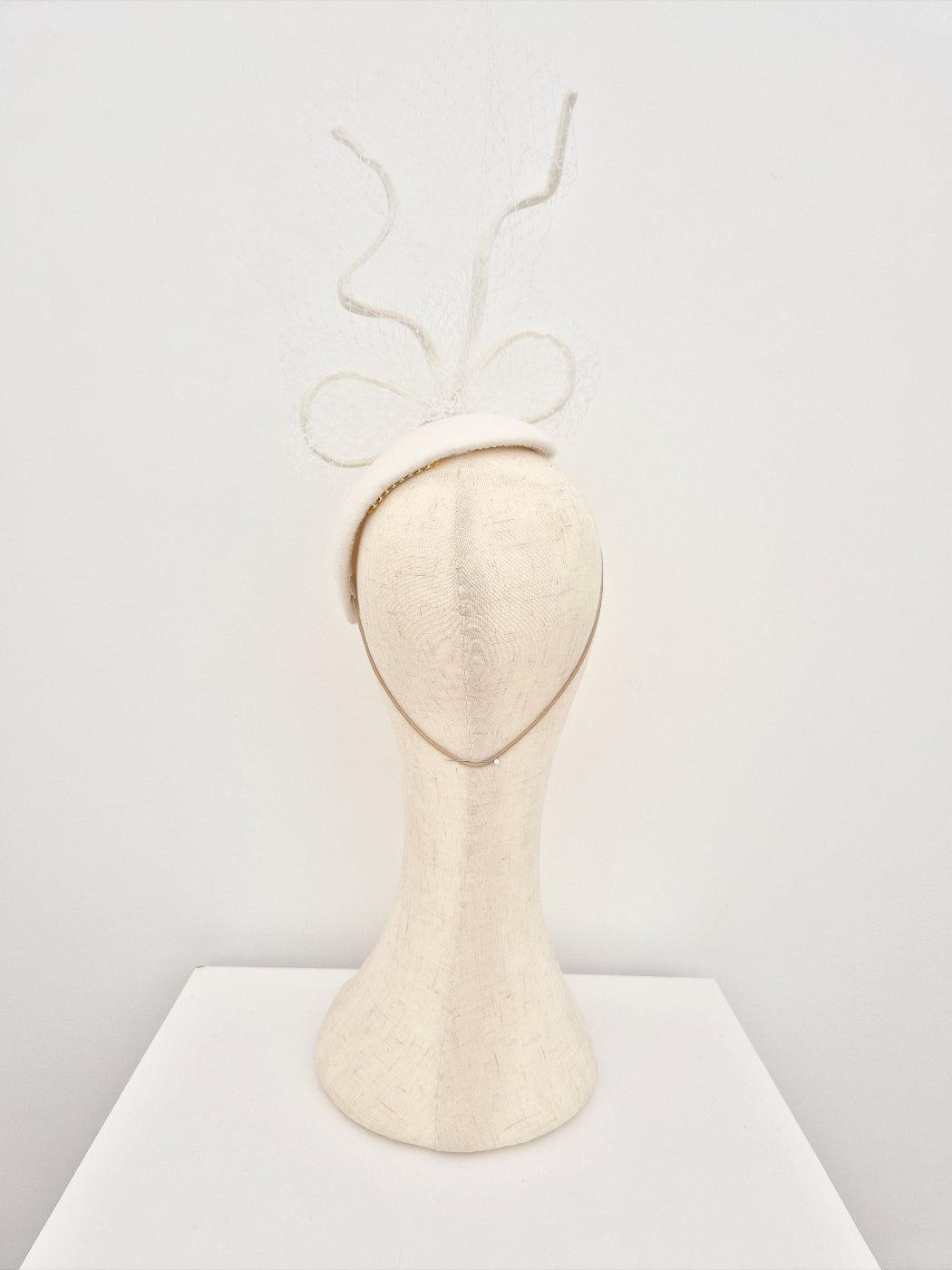 Mannequin head with a ivory headpiece with bow on a white background back view