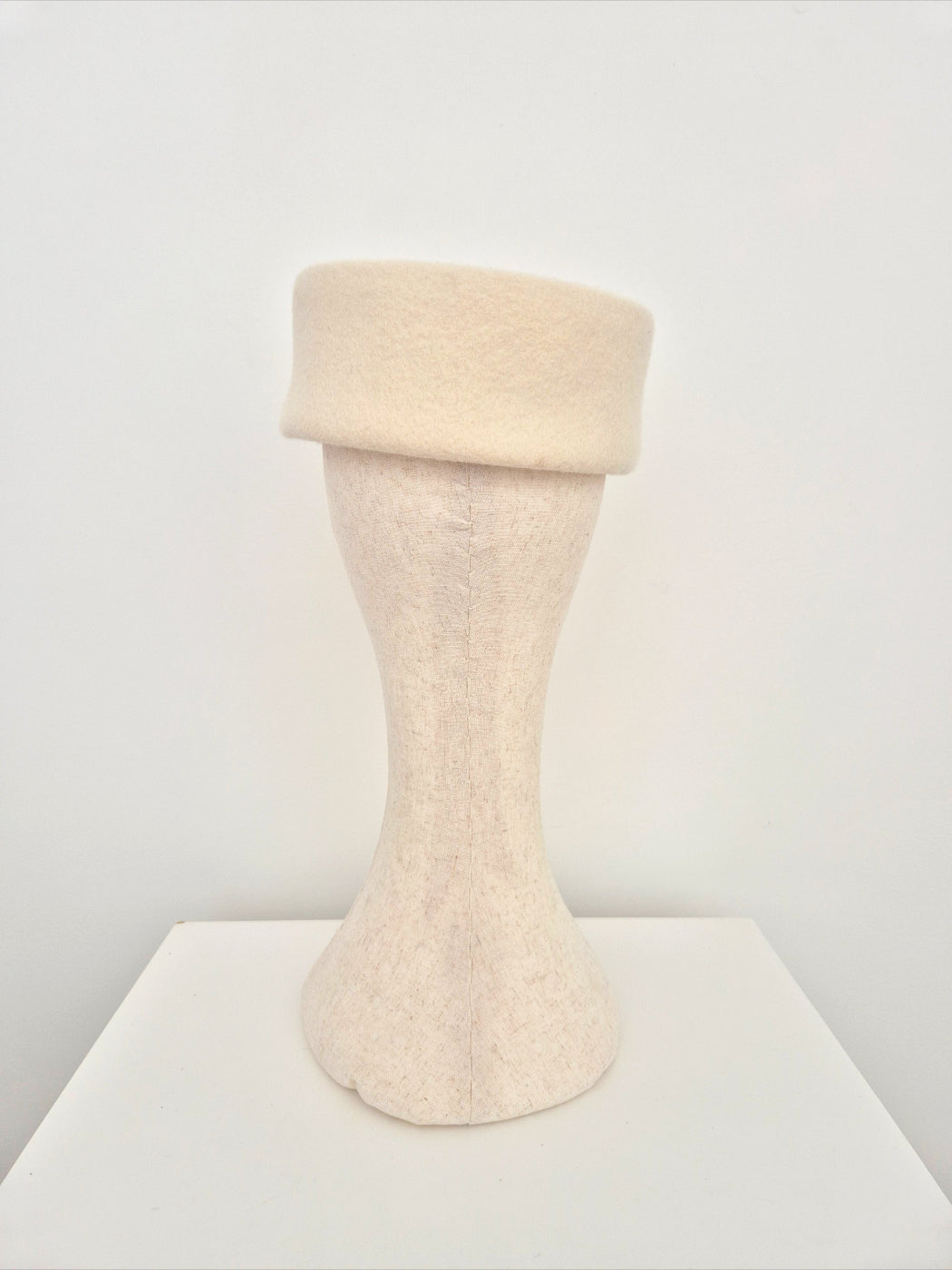 Mannequin head wearing a beige hat  on a white background back view