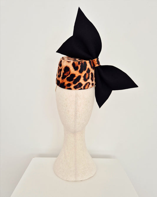 Leopard print headpiece with a black bow on a mannequin head against a white background